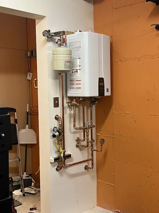 Plumbing technician inspecting water heater connections in New London